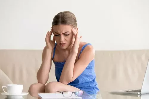 женщина с мигренью сидит на диване